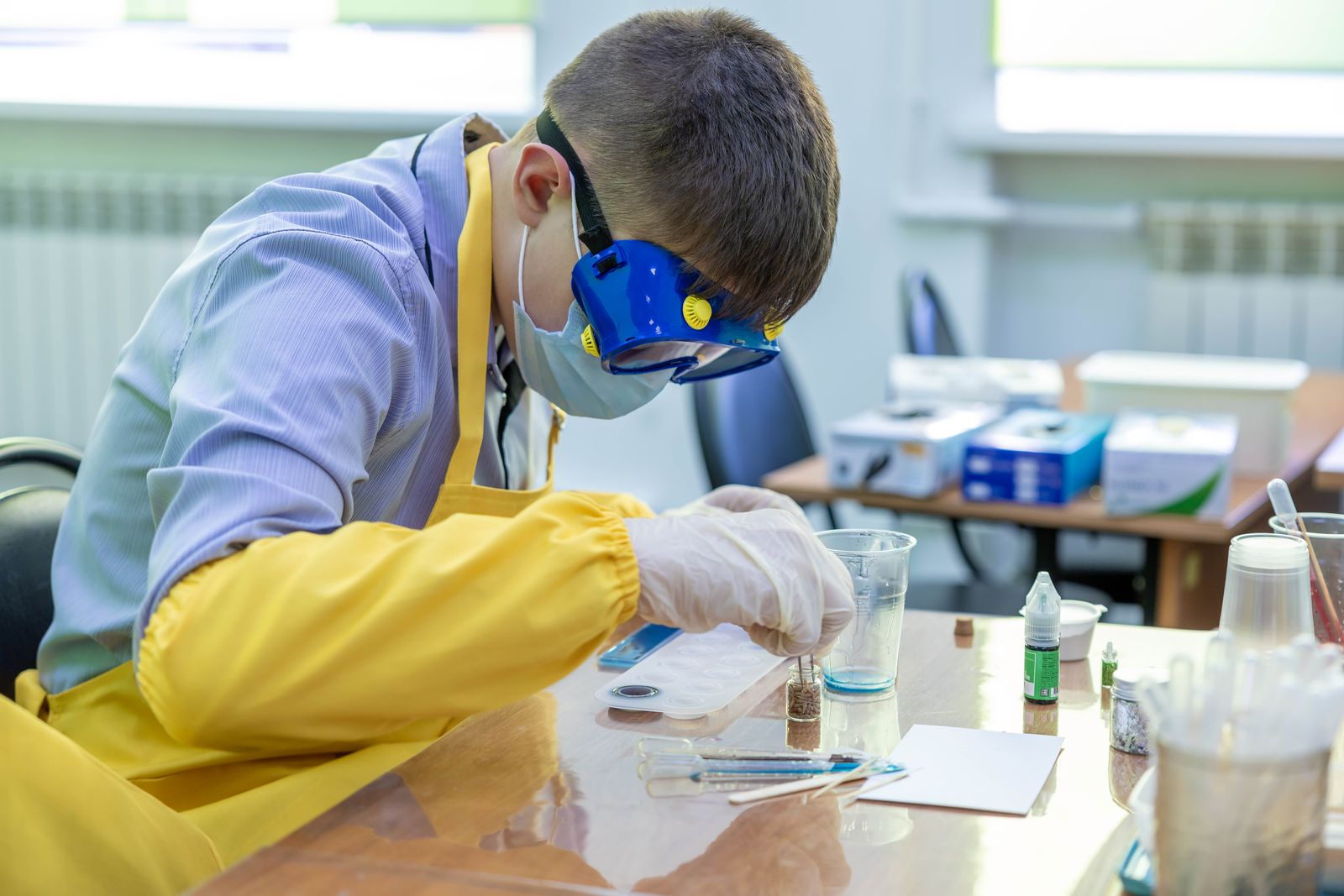 High school student in safety goggles doing a chemistry experiment in a lab